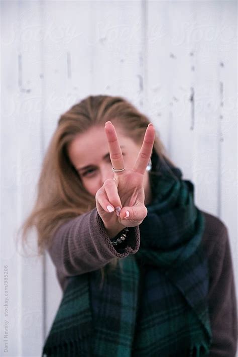 cheerful blonde girl showing peace sign at camera by stocksy