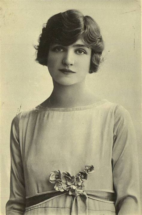 an old black and white photo of a woman wearing a dress with flowers on it