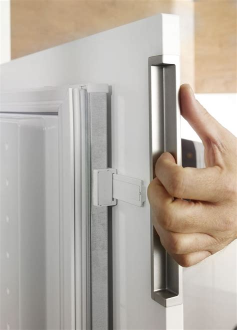 A Person S Hand On The Door Handle Of A White Refrigerator