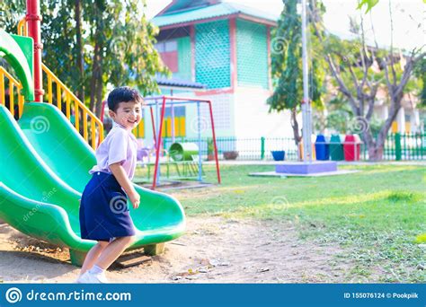 Asian Kid Playing Slide At The Playground Under The Sunlight In Summer