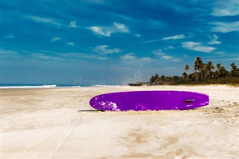 Surfboard On A Tropical Beach Overlooking The Ocean Blue Sky