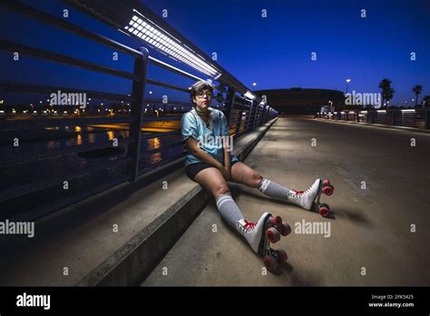 Young Caucasian Female Wearing Roller Skates Sitting On The Road At
