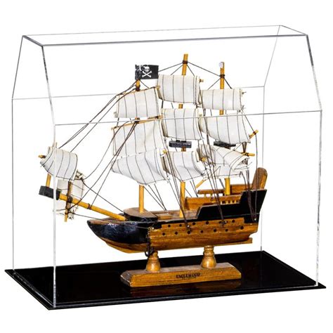 A Model Ship In A Glass Case On A Black Stand With White Sails And Two