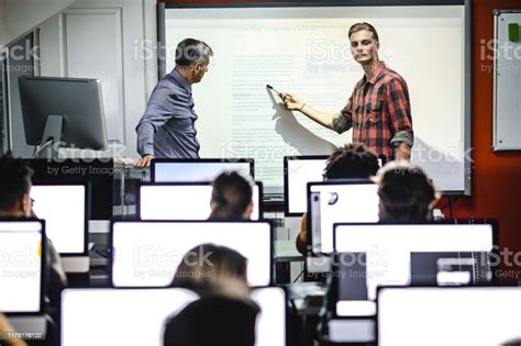 Male Student Presenting A Lecture With Teacher At Computer Class Stock