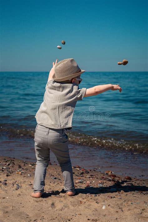 The Little Boy By The Sea Throws Stones In Water Happy Childhood Stock