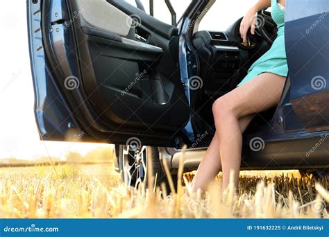 Bare Legs Of A Woman Driver Standing Near Her Car In Summer Field Stock