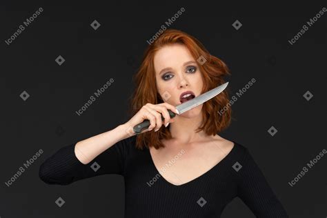 A Sexy Woman Posing And Holding A Knife Near Her Mouth Photo
