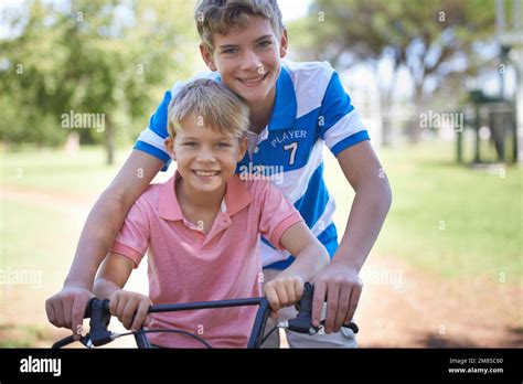 Teaching Him All He Knows About Riding Portrait Of Two Brothers Sitting On A Bicycle While
