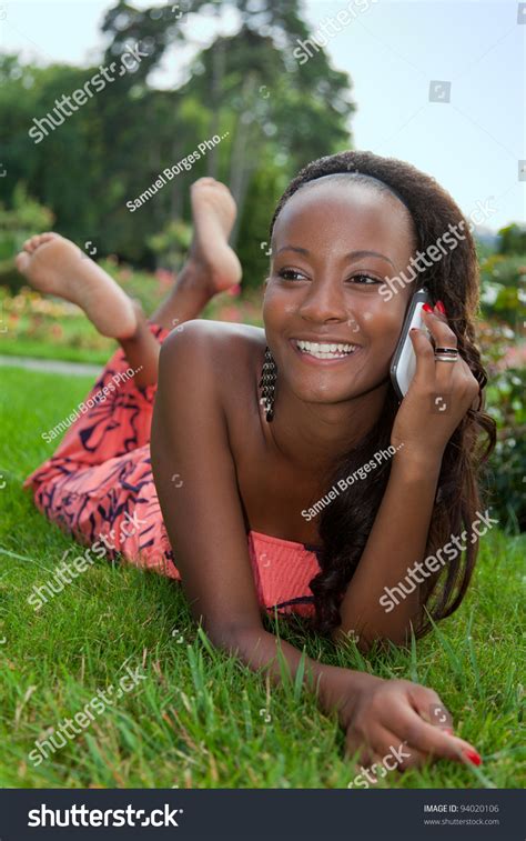 Smiling Teenage Black Girl Using A Cellphone Lying Down
