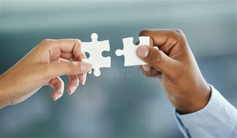 putting the pieces together cropped shot of two unrecognizable businesspeople fitting puzzle