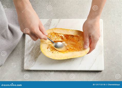 Woman Scraping Flesh Of Spaghetti Squash With Spoon On Table Stock