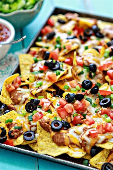 A Tray Filled With Nachos And Salsa On Top Of A Blue Tablecloth