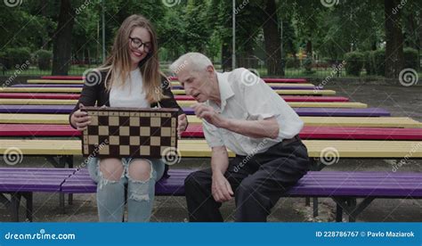 Young Girl Spends Time With An Old Man In The Park Shows Chess Him And Laughs Stock Video