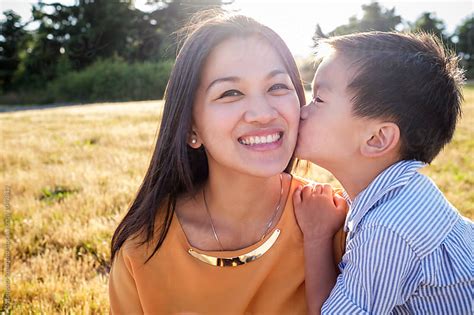 Asian Kid Kissing His Mom On The Cheek Outdoor In A Park Stock Images