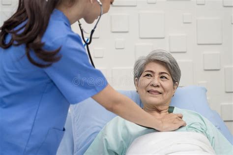 Nurse Or Doctor Is Caring For An Elderly Female Patient Lying On The