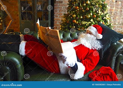 Santa Claus Reading Business Newspaper While Sitting On Sofa Stock