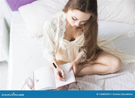 la jeune fille attirante dans une chemise de nuit s assied dans le lit et crit dans un carnet