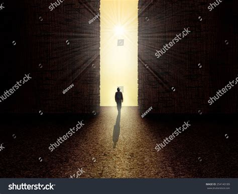 Man Walking Towards The Light From Darkness Stock Photo