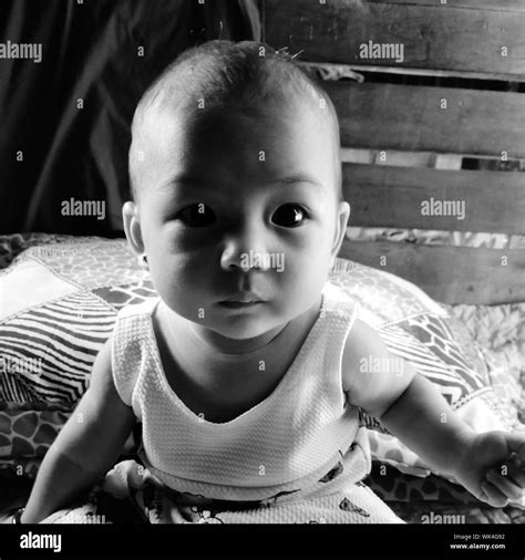 Portrait Of Cute Baby Girl Sitting On Bed At Home Stock Photo Alamy