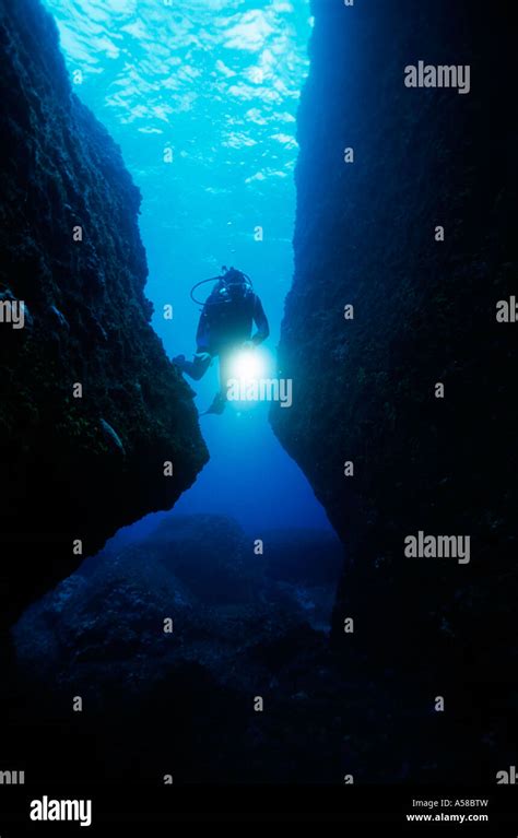 Underwater Scuba Diver Shines A Light While Swimming Through A Cave
