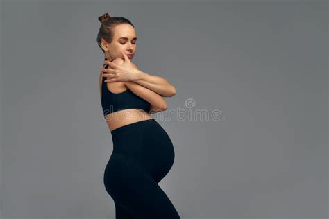 Cute Pregnant Belly On Gray Side View Of Young Pregnant Woman Embracing Herself With Hands