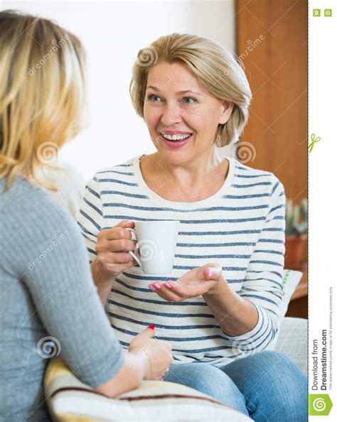Happy Daughter Sharing Gossips With Mature Mom While Tea Drinking Stock