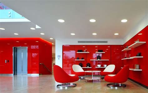 A Red Room With Two Chairs And A Table In The Center Is Lit By Recessed