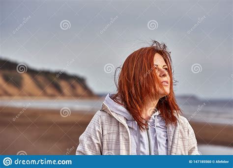 Portrait Of A Middle Aged Woman With Red Hair Walking Along The River