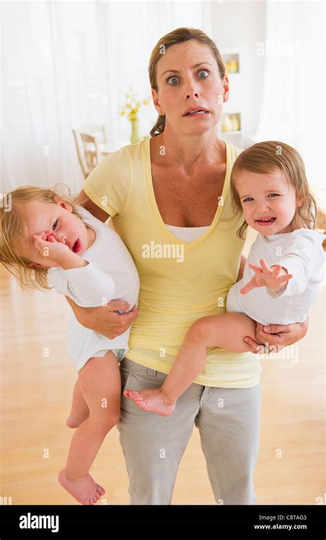 Usa New Jersey Jersey City Mother Holding Crying Daughters And Making Facial Expression Stock