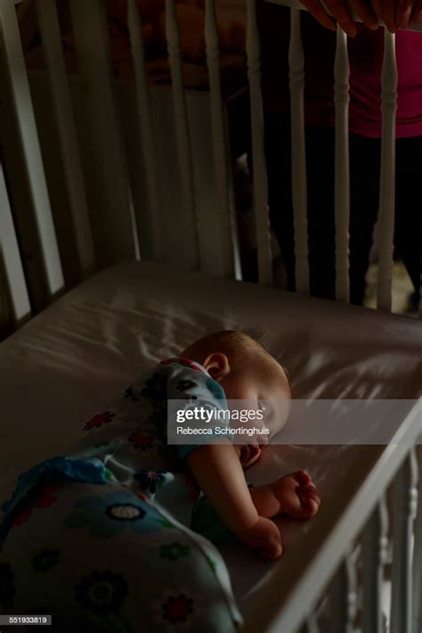Baby Asleep In Crib At Night With Mom Beside Crib High Res Stock Photo