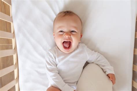 Funny Blond Cute Baby Lying And Laughing In White Children Bed Stock