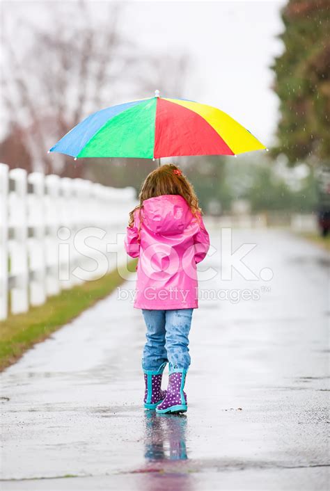 Young Girl Walking In Rain With Rainbow Umbrella Stock Photos