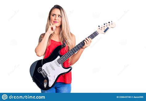 Young Beautiful Blonde Woman Playing Electric Guitar Serious Face