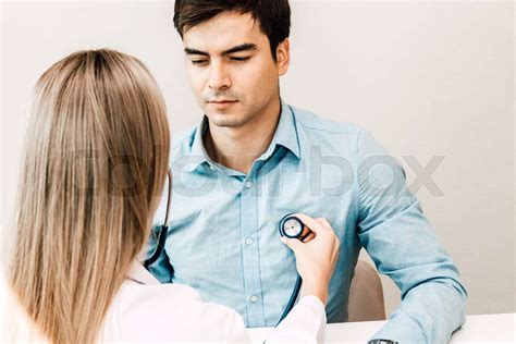 Female Doctor Examining Male Patient With Stethoscope In The Hospital Healthcare And Medicine