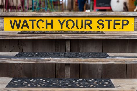Watch Your Step Sign On A Wooden Set Of Stairs