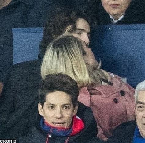 Two People Sitting Next To Each Other In The Stands At A Soccer Game With One Person Holding A