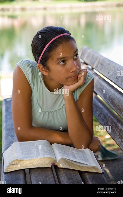 hispanic caucasian girl reading bible meditating park bench multi ethnic racial diversity