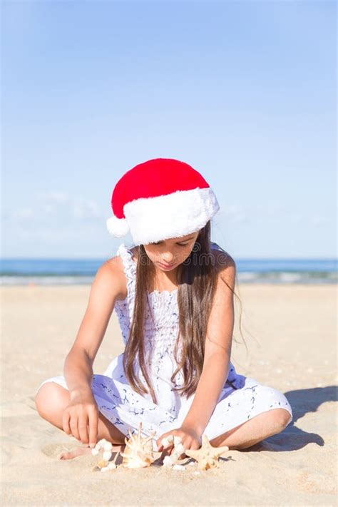 Felice Adolescente Con Un Cappello Rosso Di Babbo Natale Seduto Su Una Sabbia Su Una Spiaggia Di