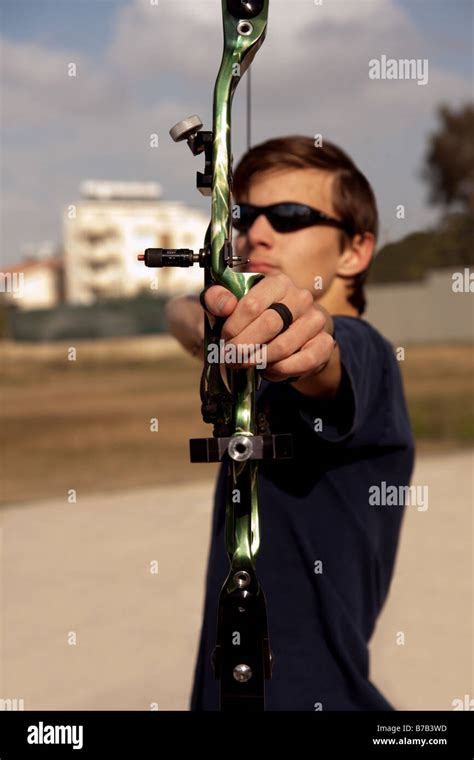 Teenage Boy Holding Archery Bow Pointed At The Camera In Portrait