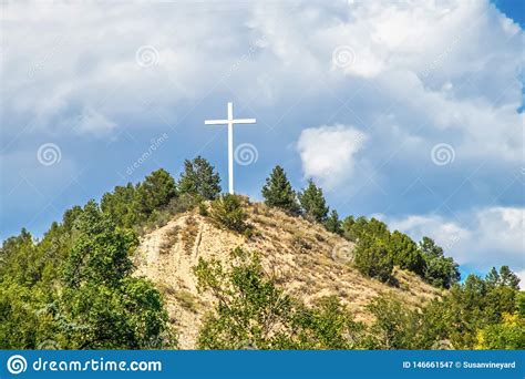 White Wooden Christian Cross On Top Of Mountain Against Stormy Sky