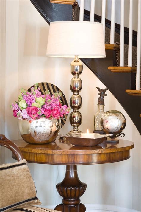 An antique pedestal table in the foyer sets the home's casual tone. Foyer table decorated with a mix of chrome & mercury glass ...
