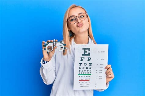 Beautiful Caucasian Optician Woman Holding Optometry Glasses And Medical Exam Looking At The