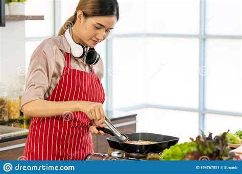 Beautiful Woman Wearing Aprons Cooking A Piece Of Delicious Salmon