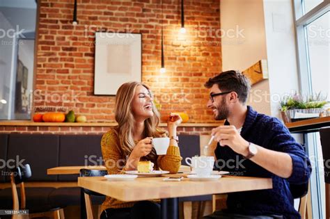 Couple Of Young People Drinking Coffee And Eating Cake In A Stylish