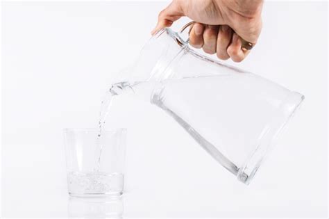 Premium Photo Hand Pouring Water From Glass Jug To Glass Isolated On