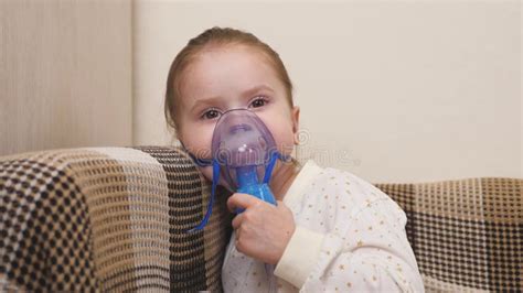 A Cute Little Baby In A Mask Breathes Through An Inhaler Home