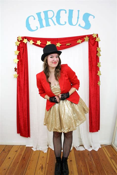 A Woman In A Red Jacket And Gold Dress Standing Next To A Circus Sign