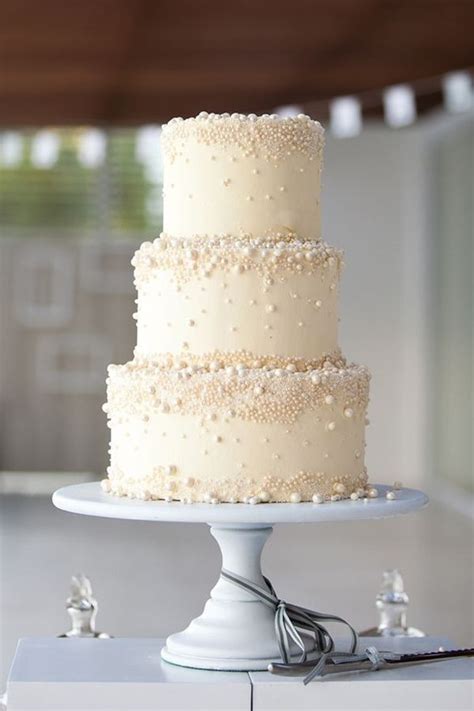 a three tiered wedding cake with white frosting and beading on the top