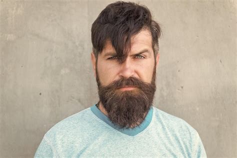 premium photo bearded and shaggy bearded man with stylish haircut on grey wall unshaven