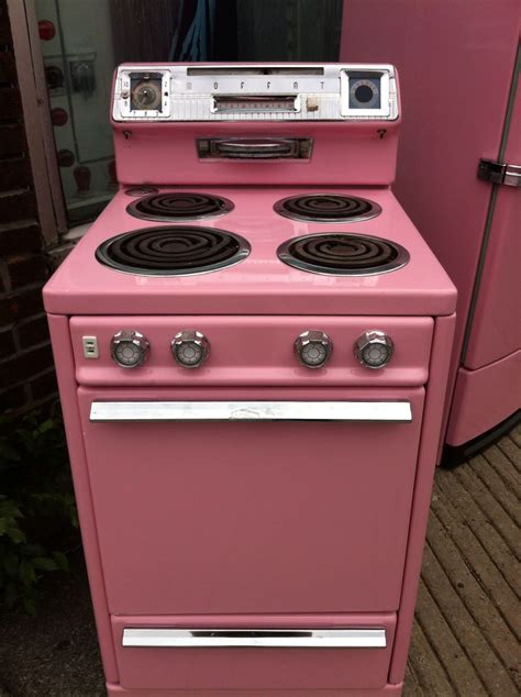 A Pink Stove Top Oven Sitting Next To A Refrigerator